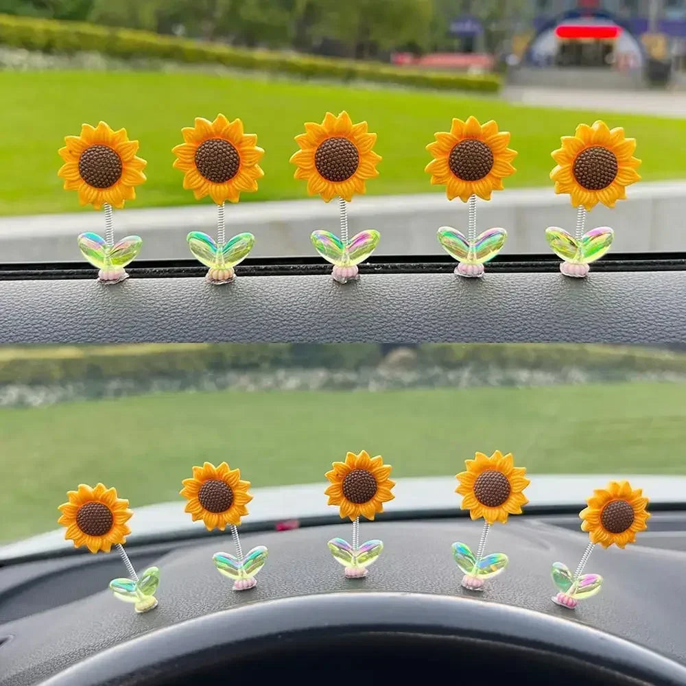 Une rangée d'ornements de tournesols jaunes et oranges sur la console d'une voiture.