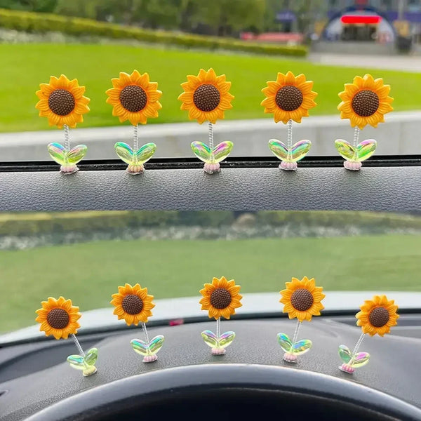 A row of yellow and orange sunflower car ornaments displayed on a car console.