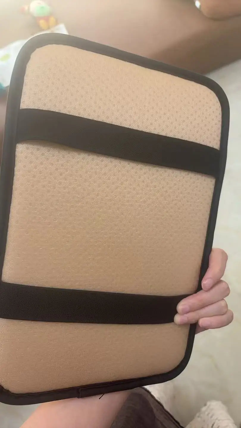 Beige Auto-Armlehnenpolster mit schwarzen Gurten, gehalten von einer Hand.
