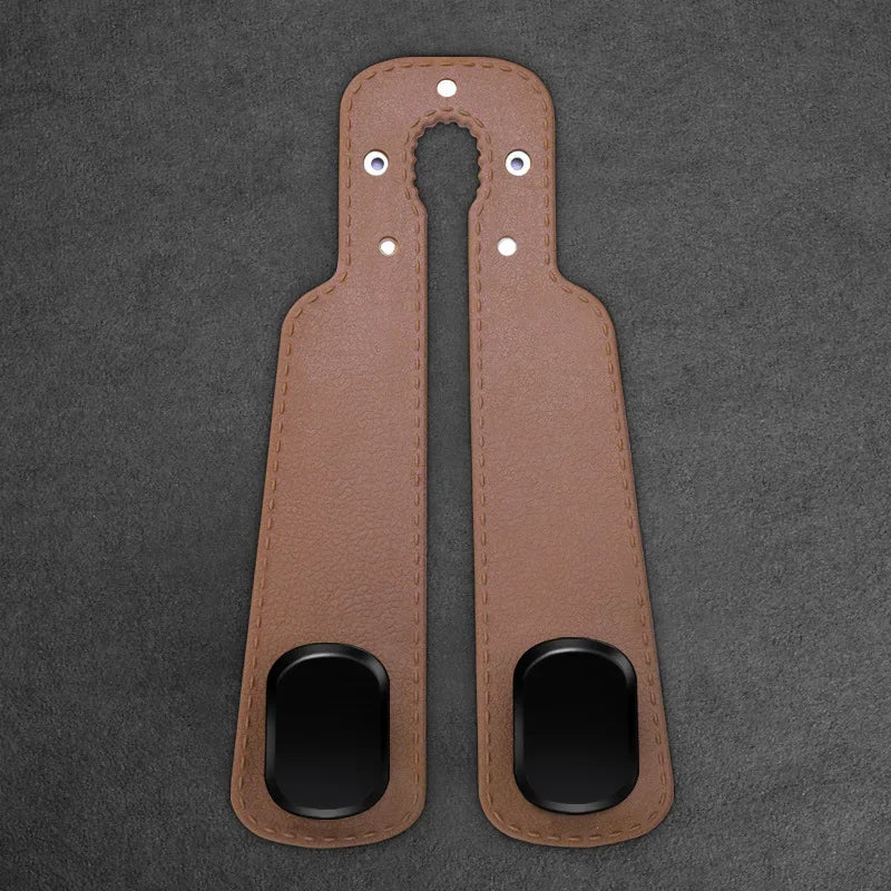 A pair of brown leather car headrest hooks with metal attachments for storage organization.