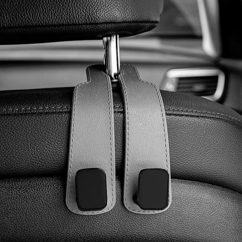 Close-up of car headrest hooks with leather straps and black grips for bag organization.
