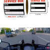 A close-up view of a motorcycle dashboard showing an oil change reminder sticker.