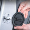 A hand is holding a black silicone car door damping guard installed on a silver car door.