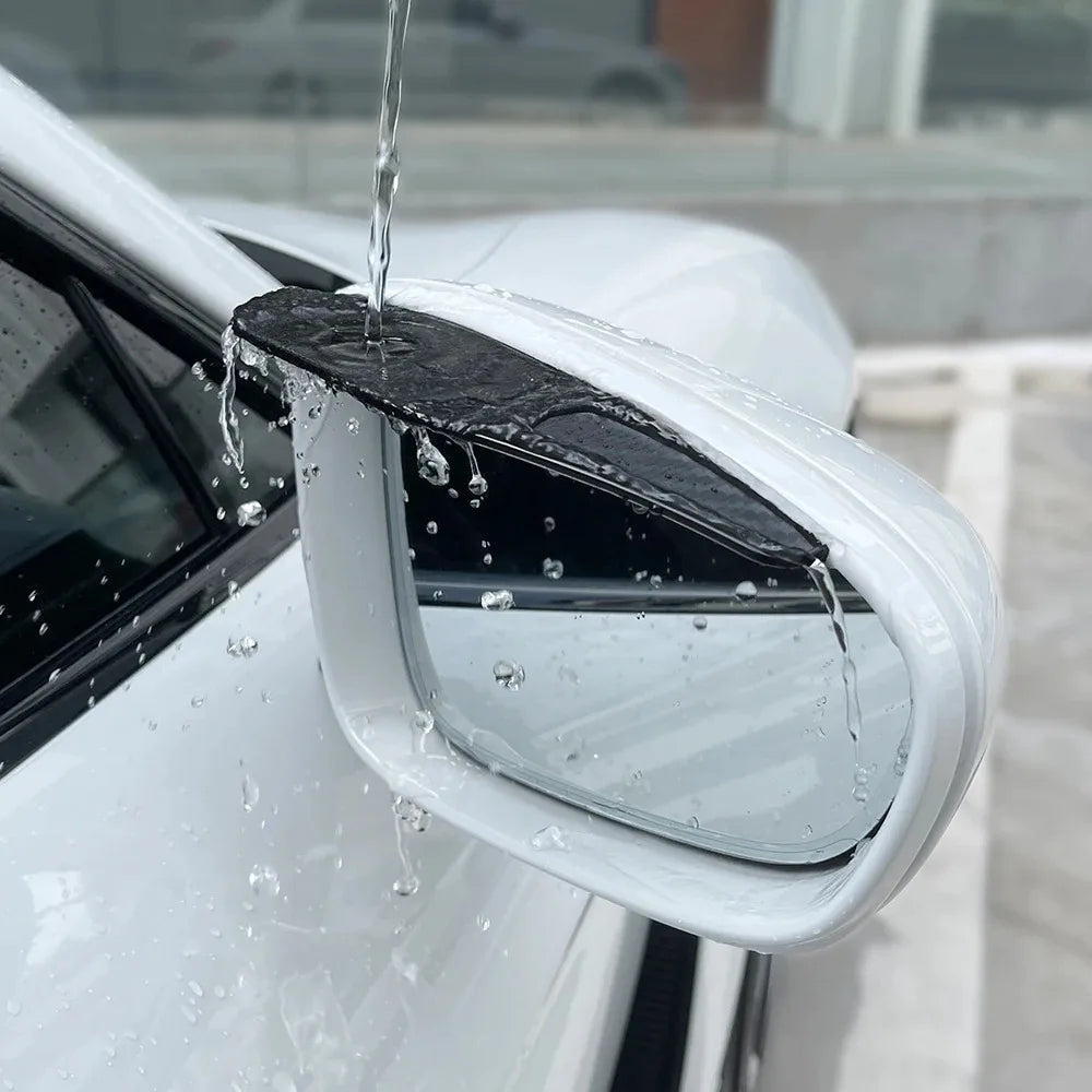 A close-up of a car's rearview mirror with a black eyebrow cover and water dripping onto the surface.