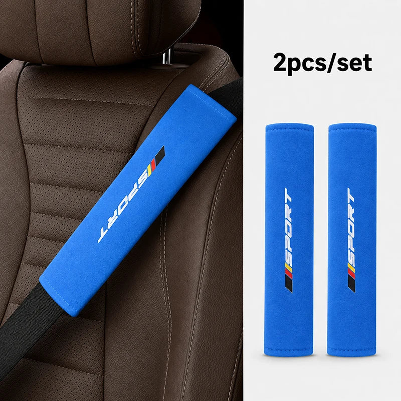 Two blue sports shoulder pads for a car seat belt, shown against a brown leather seat.