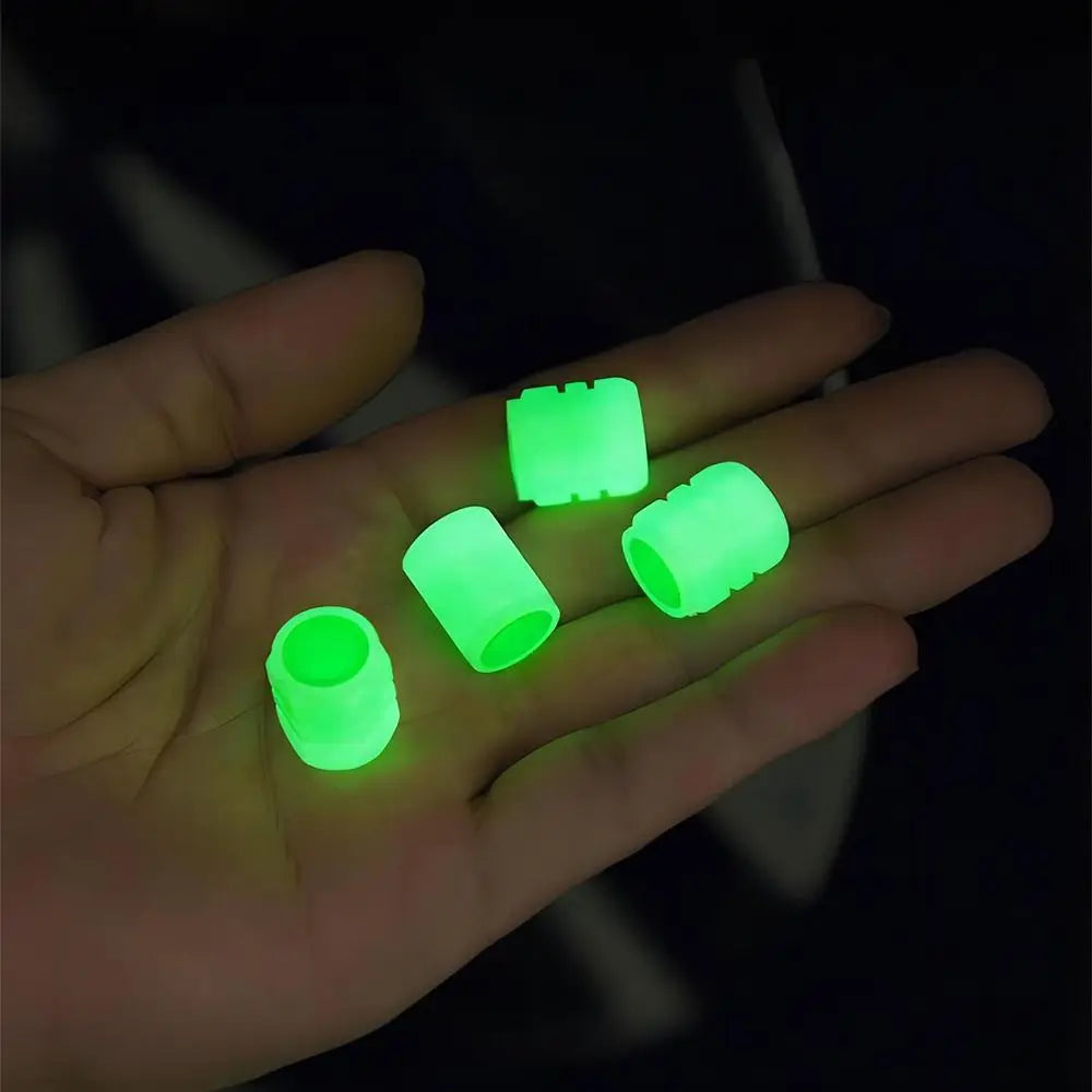 A hand holds several bright green self-luminous tire valve caps against a dark background.