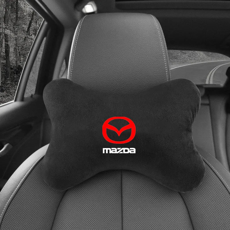 Black Mazda logo headrest seat belt shoulder pad placed on a car seat.