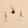 Gold-toned universal car key fob cover with a floral charm and tag