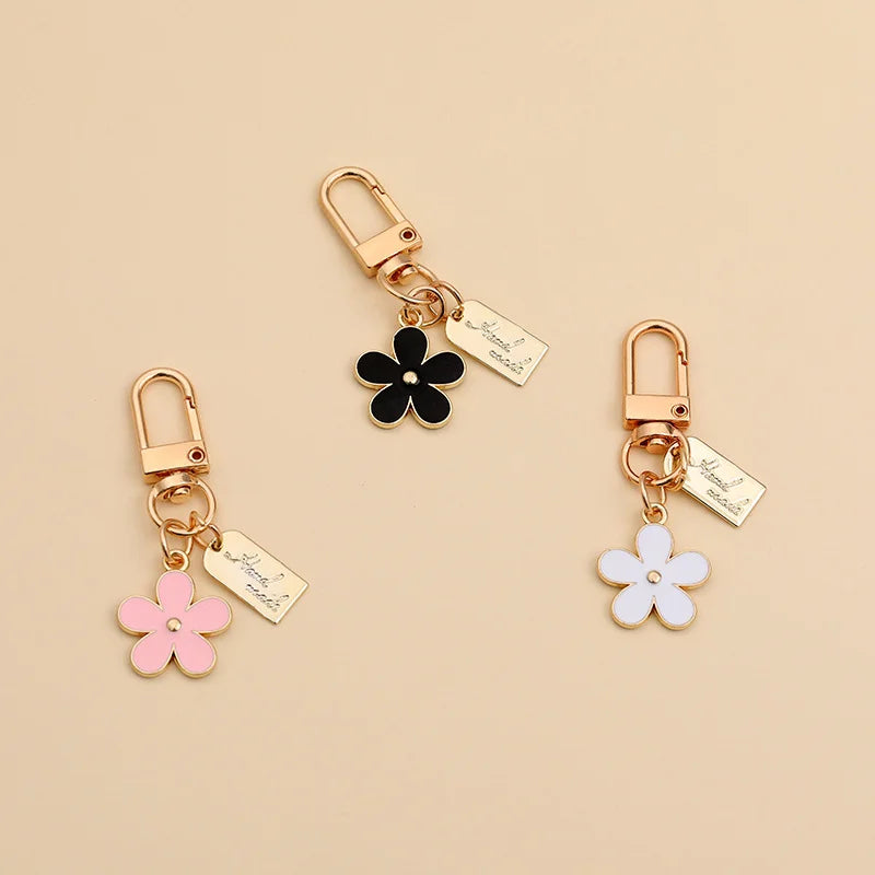 Gold-toned universal car key fob cover with a floral charm and tag