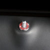 A silver car door lock pin trim set with a red gemstone accent is shown on a black leather surface.