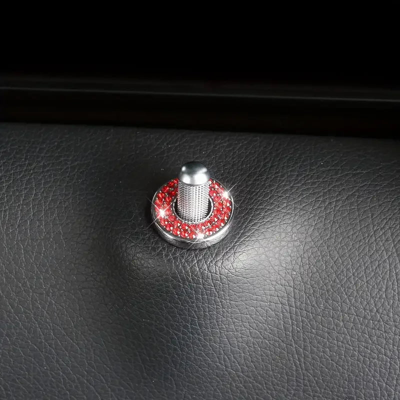 A silver car door lock pin trim set with a red gemstone accent is shown on a black leather surface.