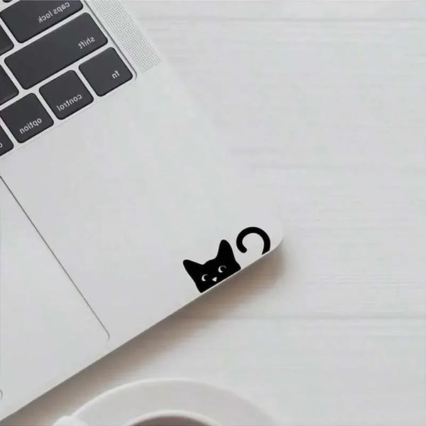 A white laptop with a black cat decal on the lid, placed next to a white cup.