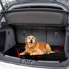 A golden retriever lies on a black outdoor car trunk mat inside an open car trunk.