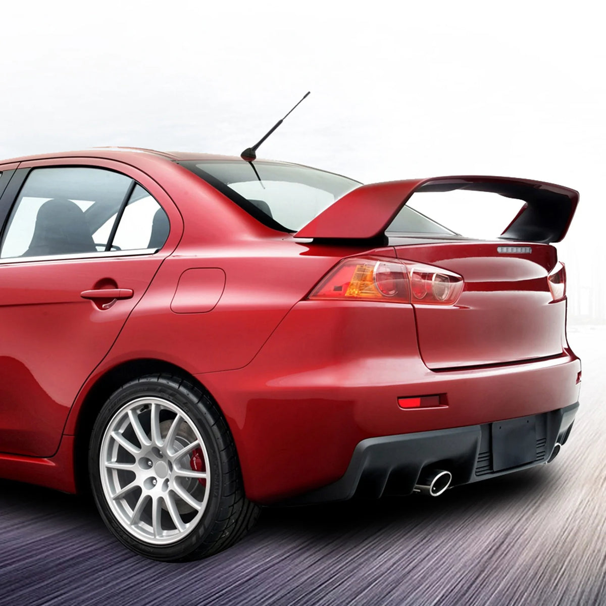 A red sports car with a black spoiler and antenna is shown from the rear three-quarter angle.