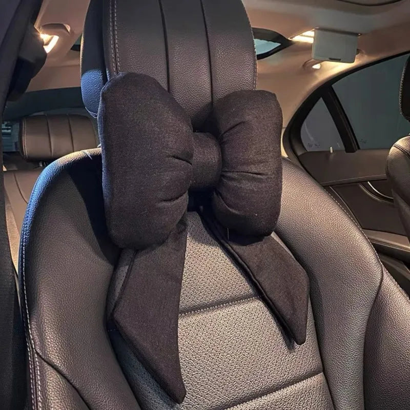 Un oreiller de cou noir en forme de papillon est fixé à l'appui-tête d'une voiture intérieur.