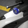 Primer plano de empuñaduras metálicas azules CNC con carcasa negra y un perno plateado en un componente de motocicleta blanca