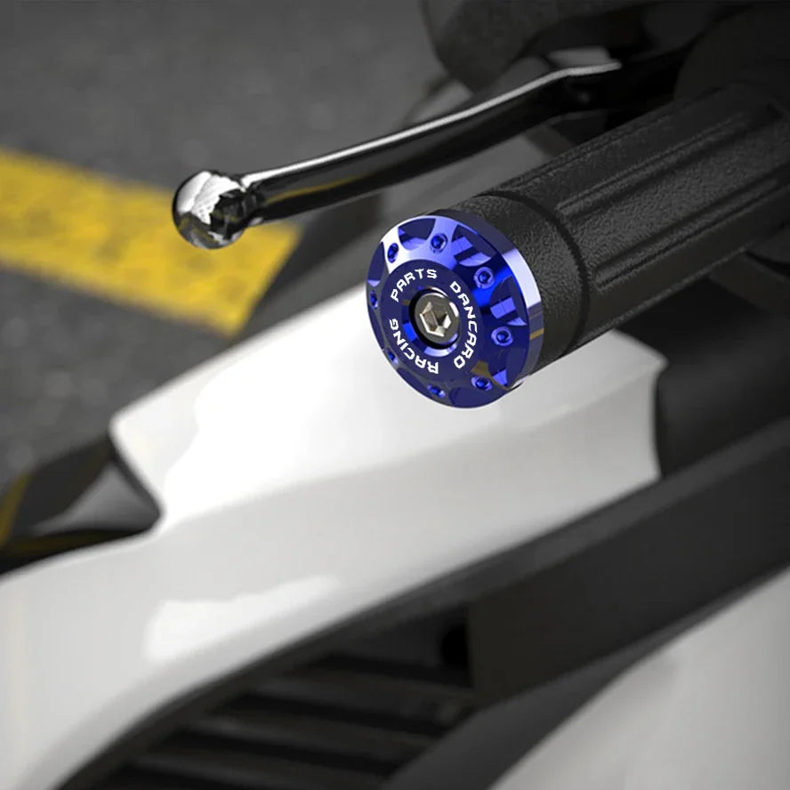 Primer plano de empuñaduras metálicas azules CNC con carcasa negra y un perno plateado en un componente de motocicleta blanca