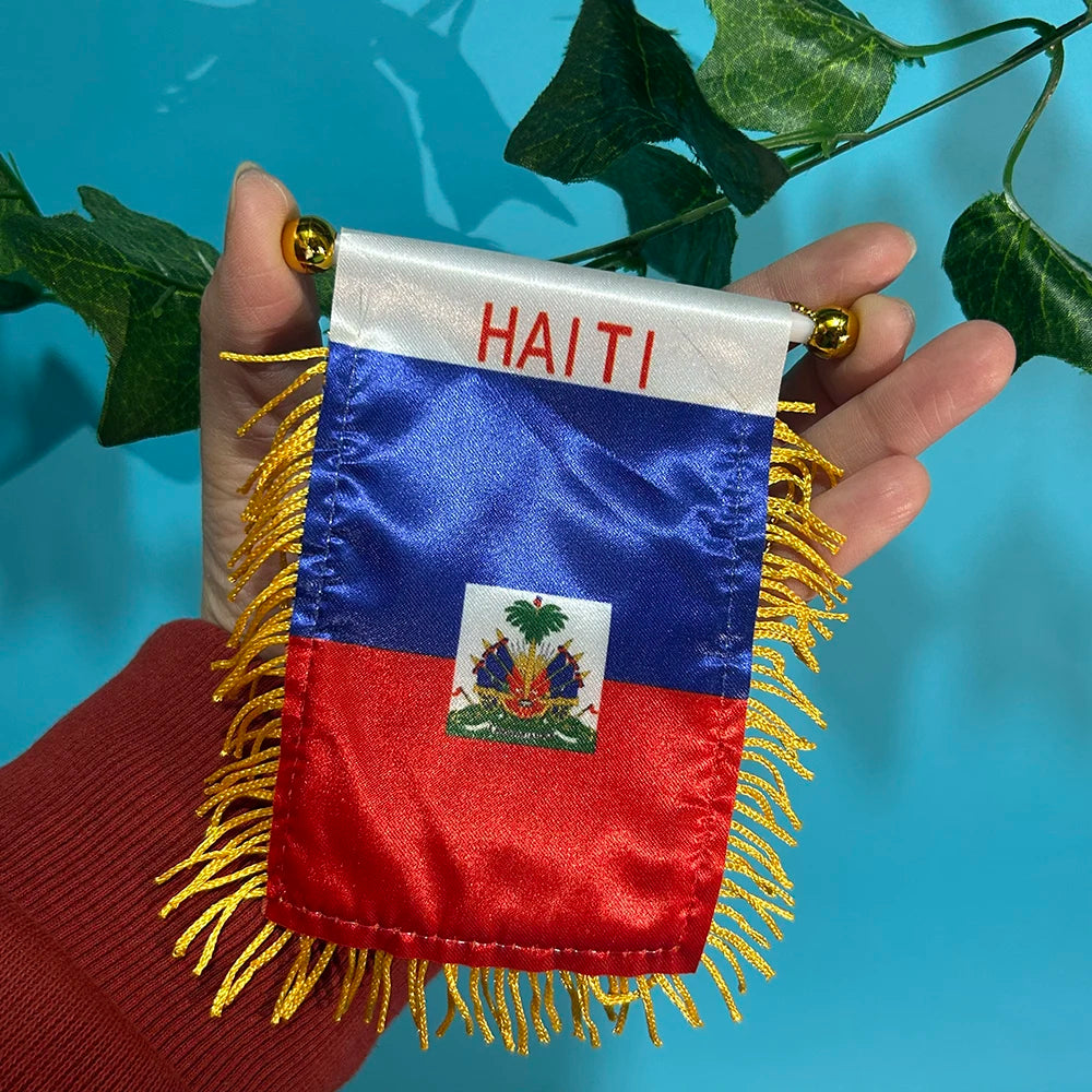 A double-sided polyester flag of Haiti featuring the national colors and the word HAITI, held in a hand against a blue backgr
