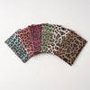 A collection of leopard print fabric pouches or passport holders in various shades of brown, pink, and green.