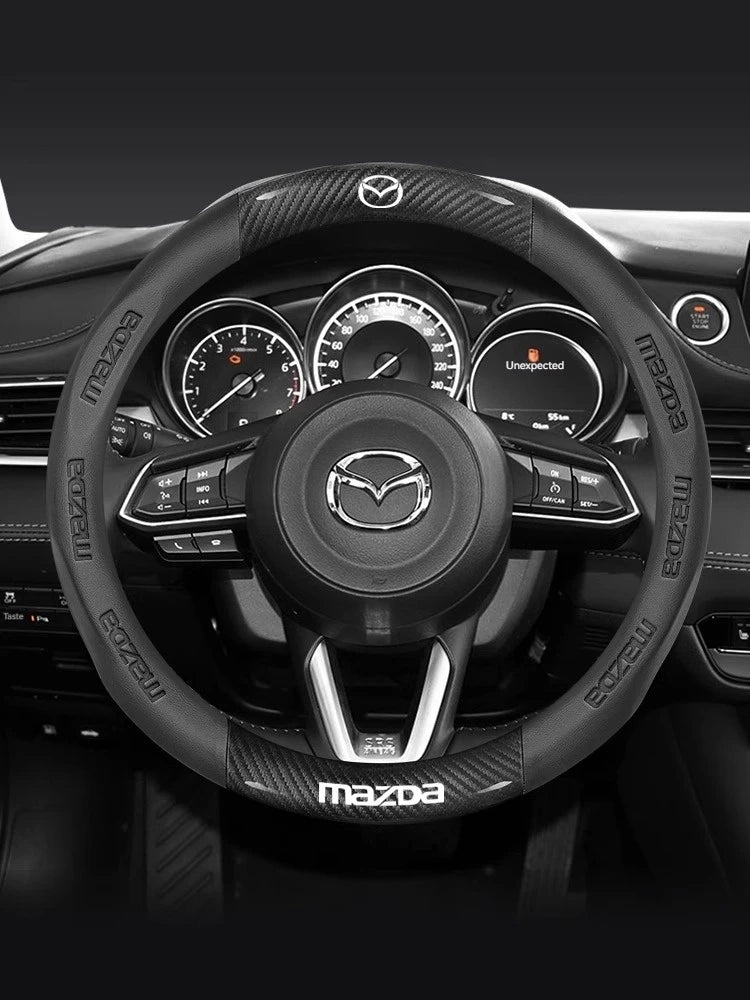 Gros plan d'une housse de volant en fibre de carbone noire pour l'intérieur d'une voiture Mazda.