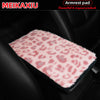 Pink leopard print plush armrest pad covering a black car seat.