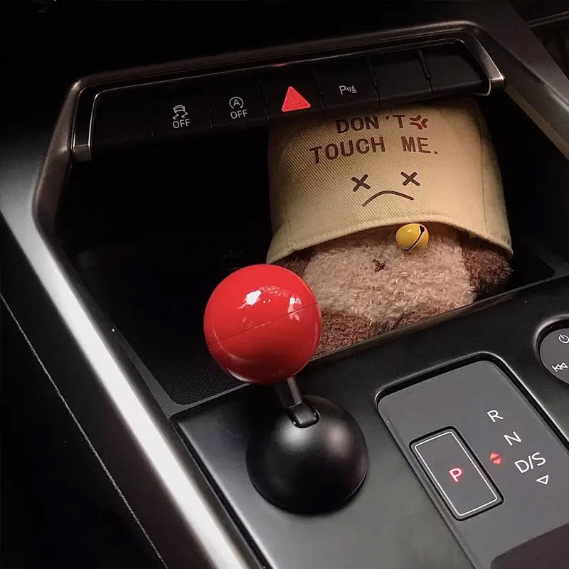 A close-up view of a push start ignition button cover with a fuzzy brown material and a red knob.