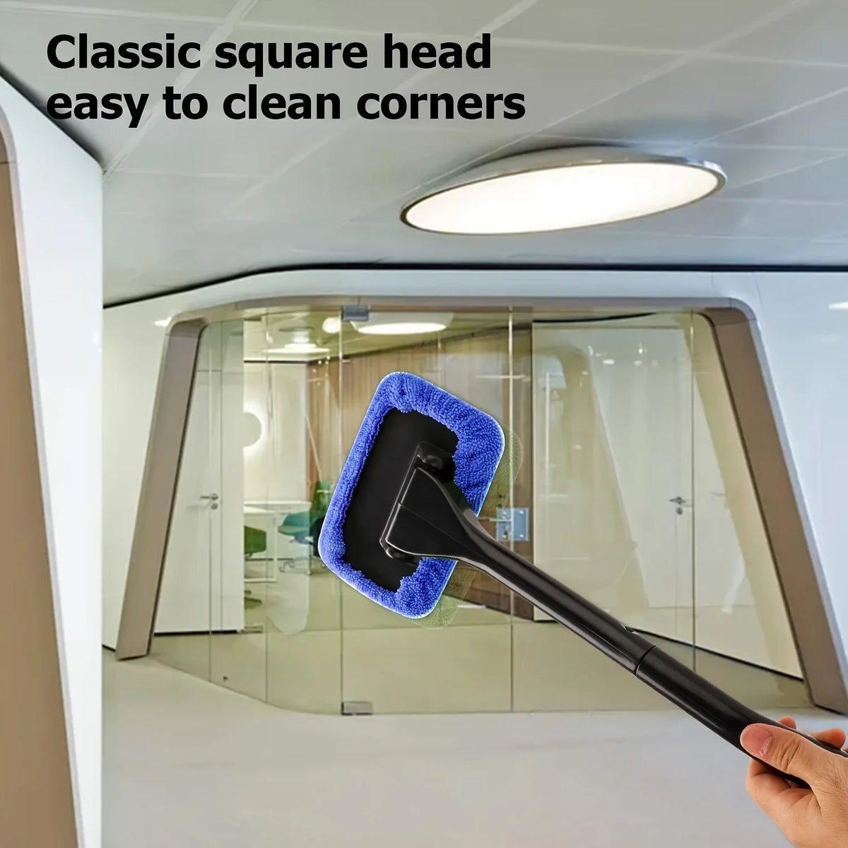 A hand holds a classic square head cleaning tool with a blue sponge to clean the corners of a glass partition.