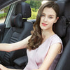 A young woman sits in a car seat, wearing a light pink top, with the headrest and seatbelt pads visible.