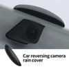 Black car reversing camera rain cover with a lens visible on a gray surface.