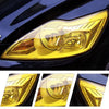 Golden yellow PVC tint film applied to a car headlight, showing a clear, yellowish lens.