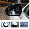 Close-up view of a black side view mirror with a rotating blind spot camera mounted on the housing.