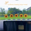 Une rangée de tournesols jaunes agitant la tête, exposés sur une console ou un miroir de voiture noire.