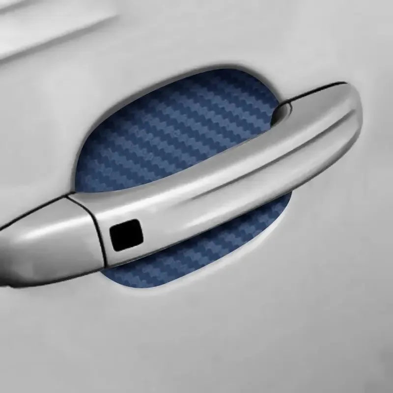 A close-up view of a silver car door handle with a blue patterned film applied to protect it.