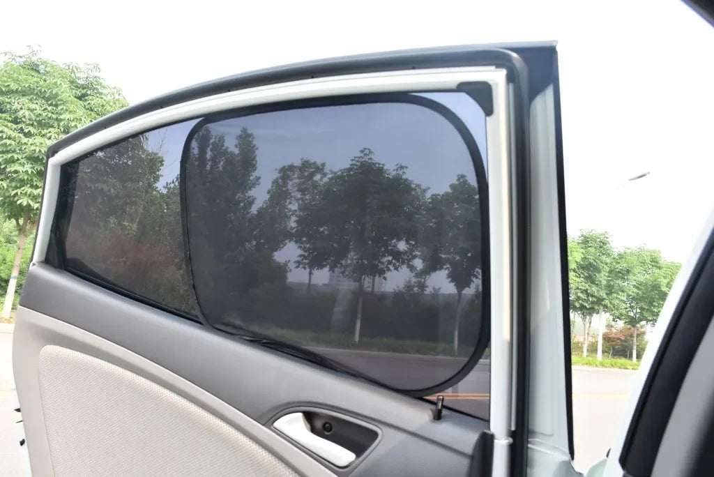 A view through a car window showing a dark mesh sun shade installed on the side of a vehicle.