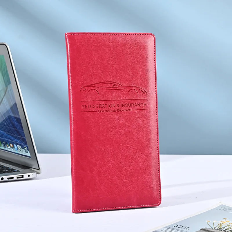 A red leather vehicle organizer with embossed text for registration and insurance documents.