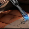 A hand is using a powerful 5-in-1 portable wireless car vacuum to clean dust from a leather car interior.
