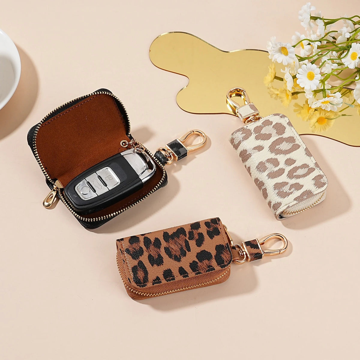 A collection of leopard print car key holders in brown and beige leather, displayed on a light background.