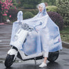 A person wearing a transparent windproof motorcycle rain poncho is sitting on a white scooter on a wet road.