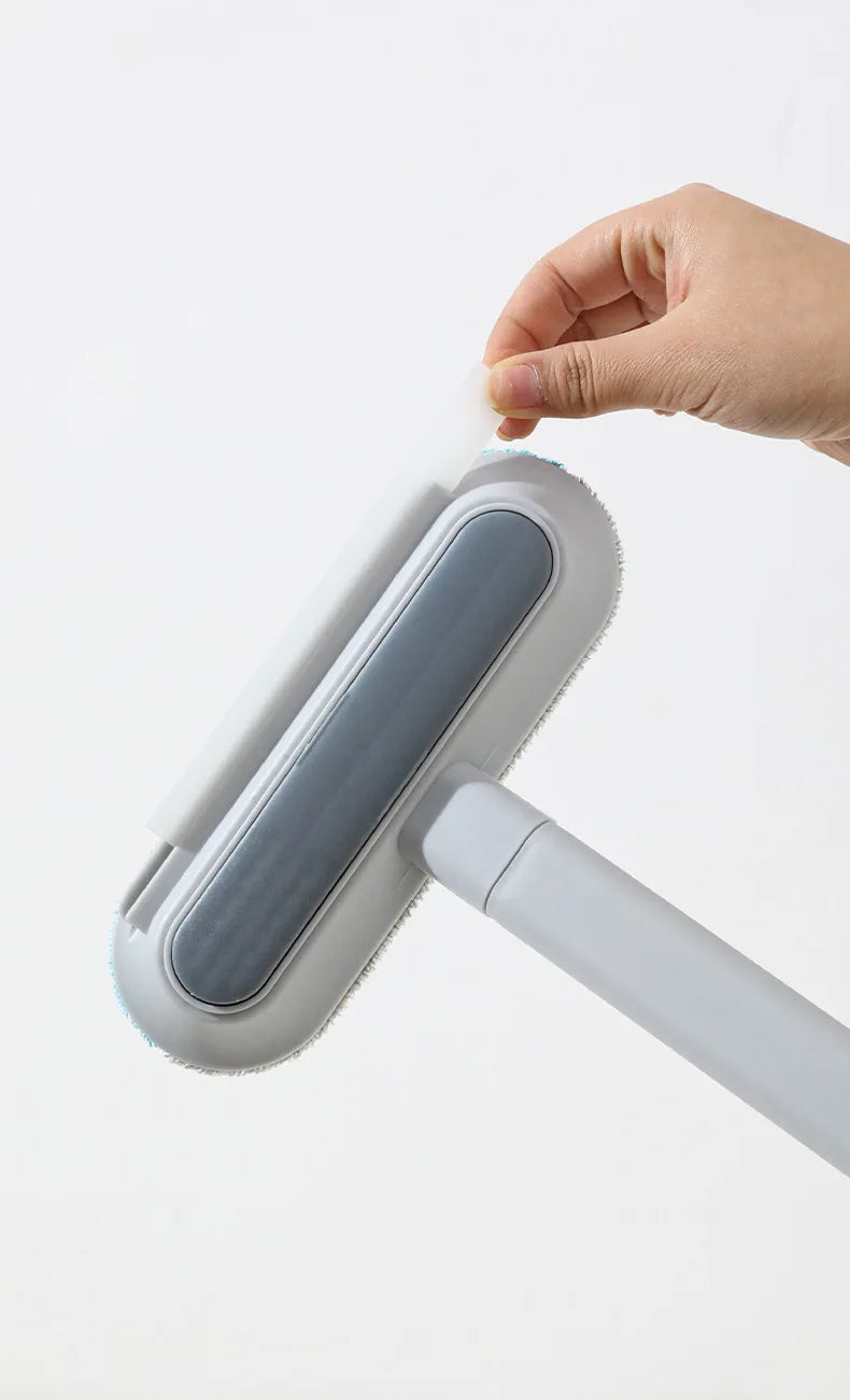 A hand is holding a white static pet hair remover brush with a gray head against a white background.