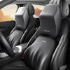 Close-up view of black leather car seats with ergonomic lumbar and neck support cushions.