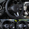 Close-up view of a black anti-slip leather steering wheel cover inside a car cockpit.