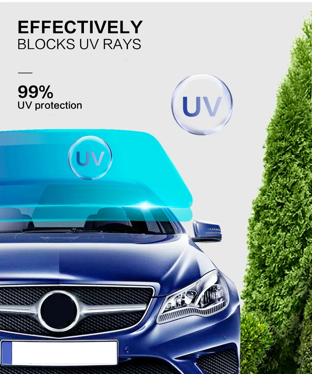 Gros plan sur le pare-brise d'une voiture bleue avec film de protection UV, une haie verte en arrière-plan.