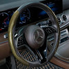 Nahaufnahme eines schwarzen Lenkrads mit Lederbezug und silbernem Mercedes-Emblem.