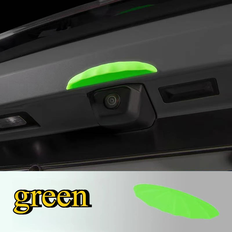 A close-up view of a green universal car rain shield and rear camera cover installed on a vehicle's exterior.