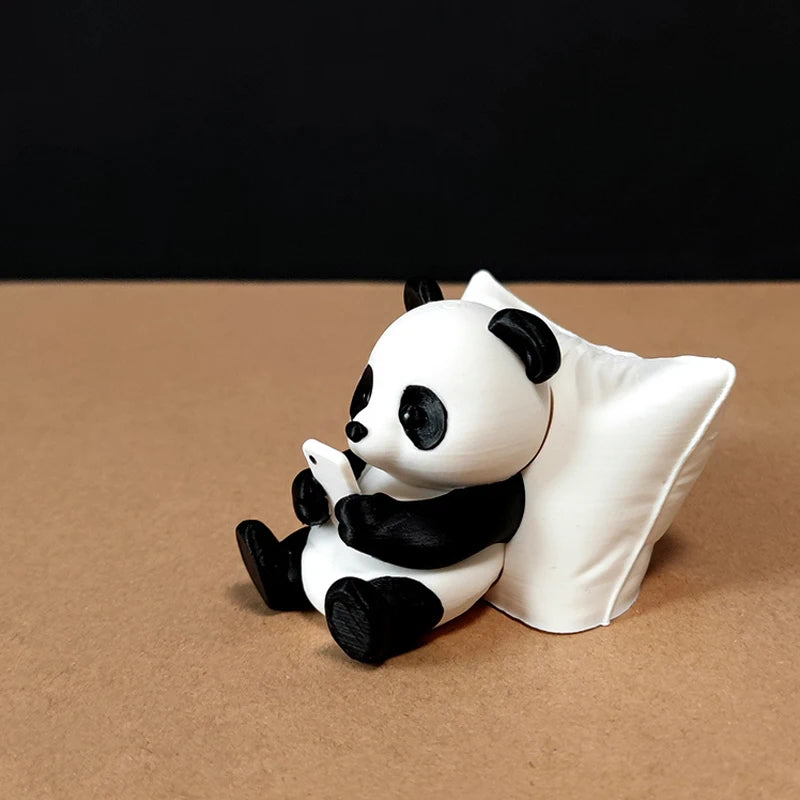 A white and black panda sculpture desk ornament sitting on a brown surface.