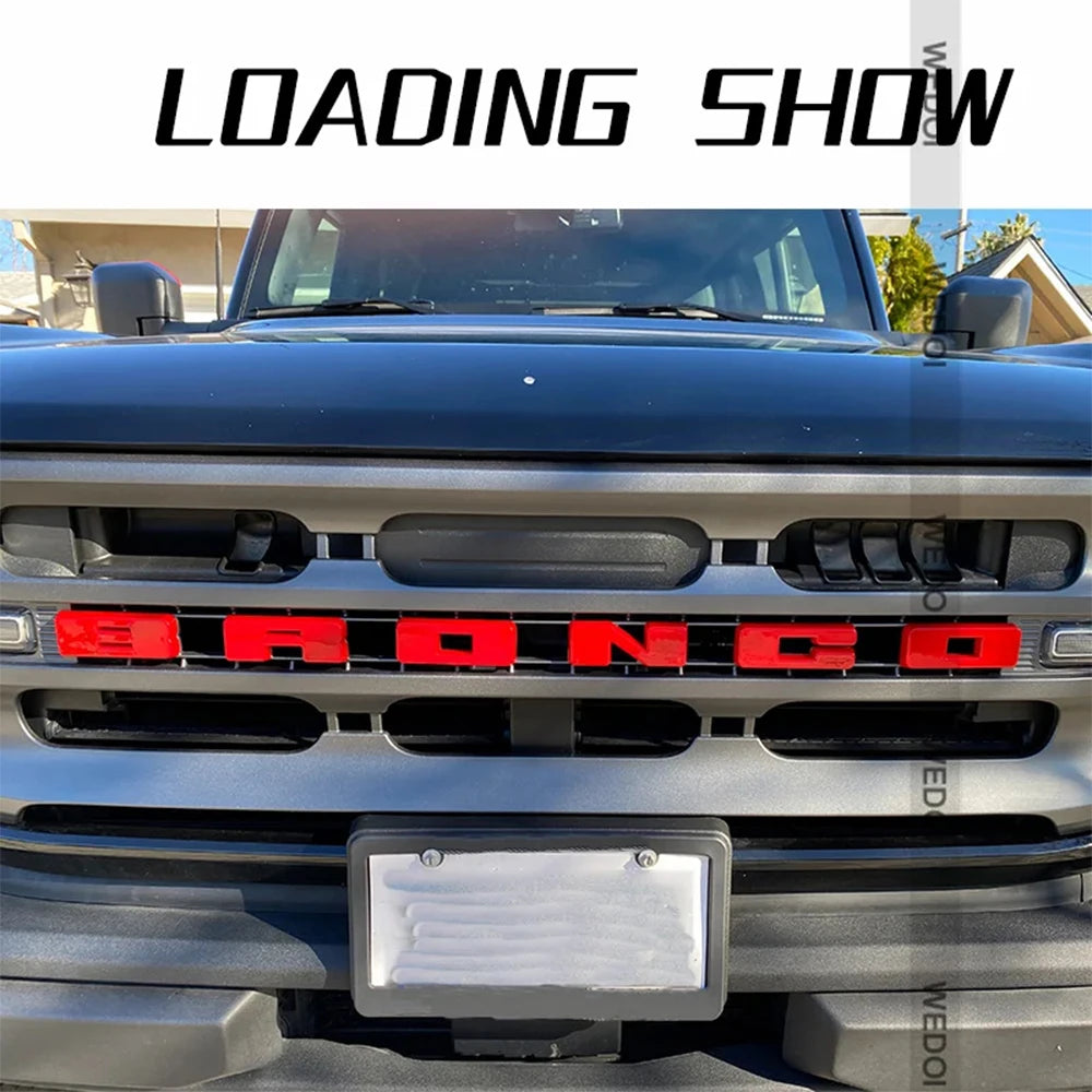 Gros plan de la calandre noire d'un Ford Bronco avec une plaque de lettres rouge installée.