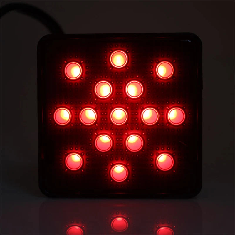 Schwarzes rechteckiges LED-Bremslicht mit mehreren roten runden Lichtern, reflektierend auf einer glänzenden Oberfläche.