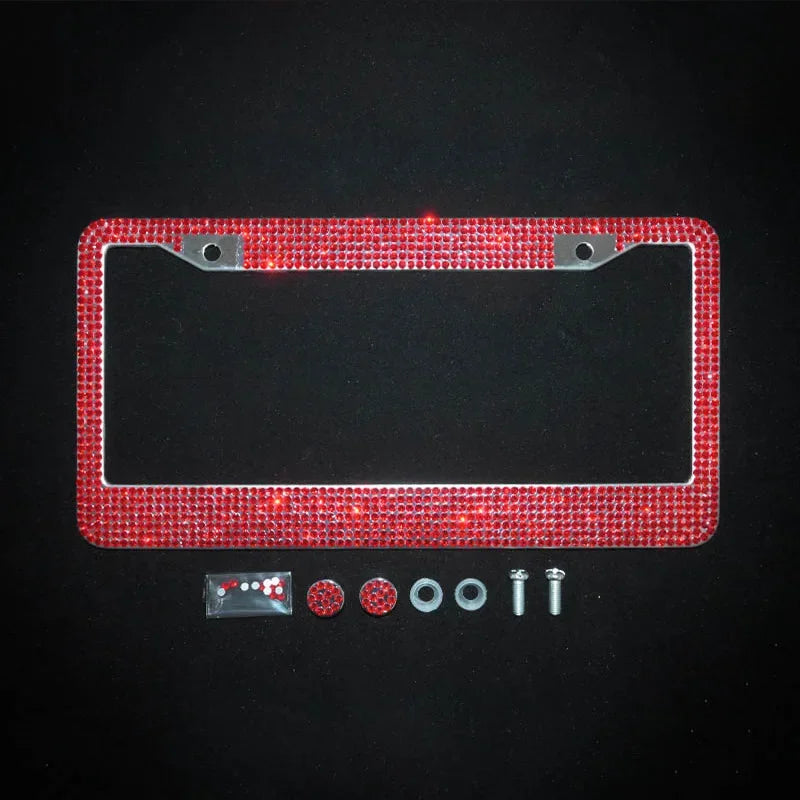 A rectangular license plate frame covered in red crystal rhinestones with a clear plastic cover and mounting hardware.