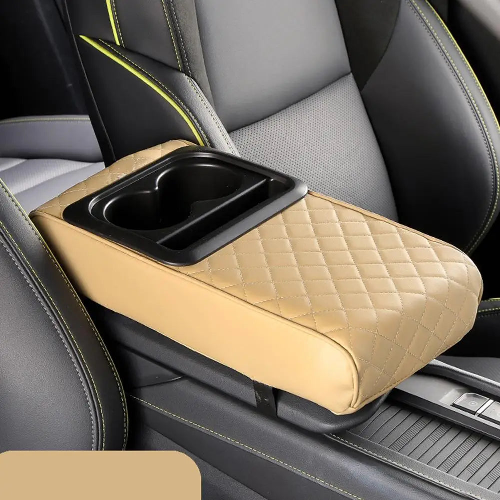 A tan car armrest cushion with a black integrated cup holder is placed on a gray and black car seat.