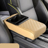 A tan padded armrest cushion with an integrated cup holder is placed on a dark car seat.